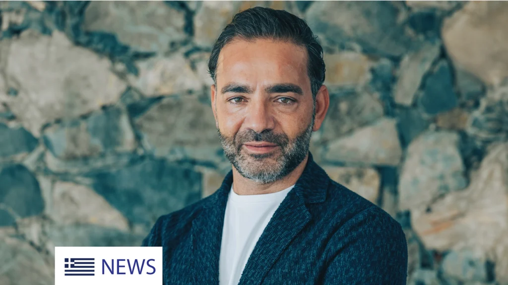 Yiannis Misirlis, Chairman at Imperio Group and LBDA, dressed in a dark blue jacket, standing in front of a stone wall