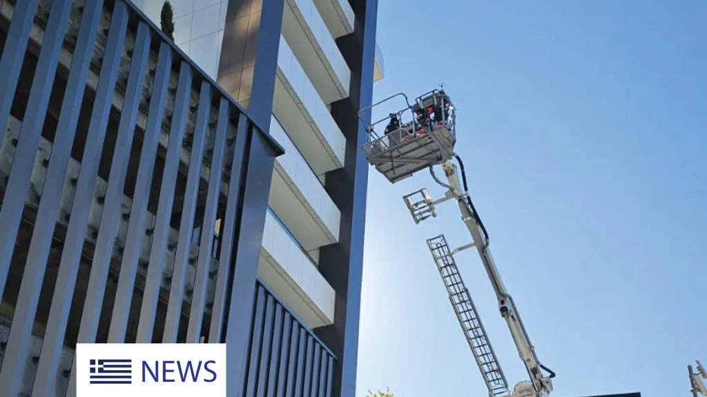 Firefighters conduct a high-rise rescue drill using an aerial platform outside a modern residential building.