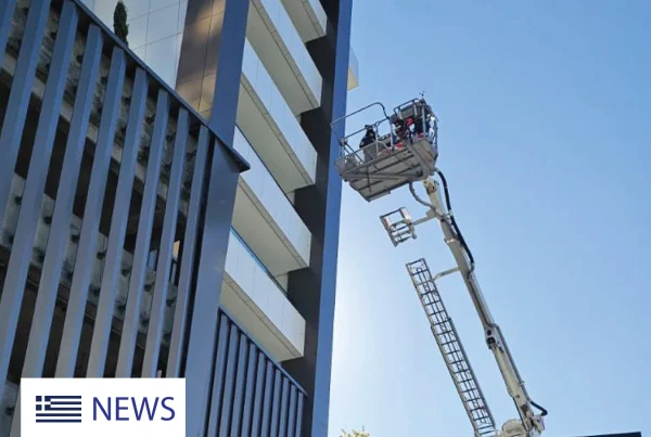 Firefighters conduct a high-rise rescue drill using an aerial platform outside a modern residential building.